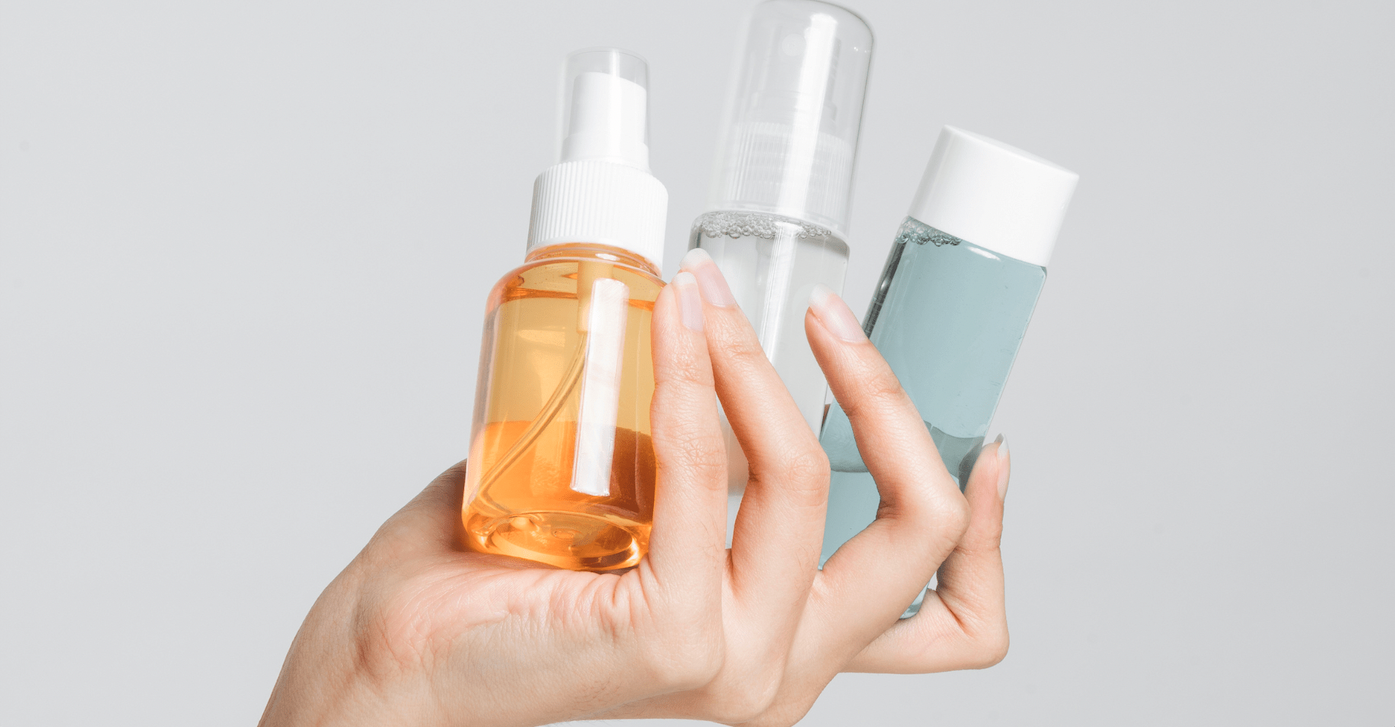 a hand holding three bottles of personal care products