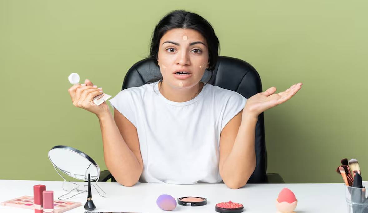 Beautiful woman sits table with makeup tools applying tone cream spreading hands