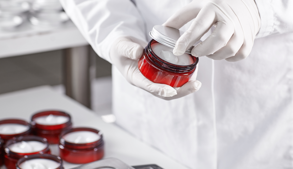 Worker filling a beauty product container with cream cosmetic