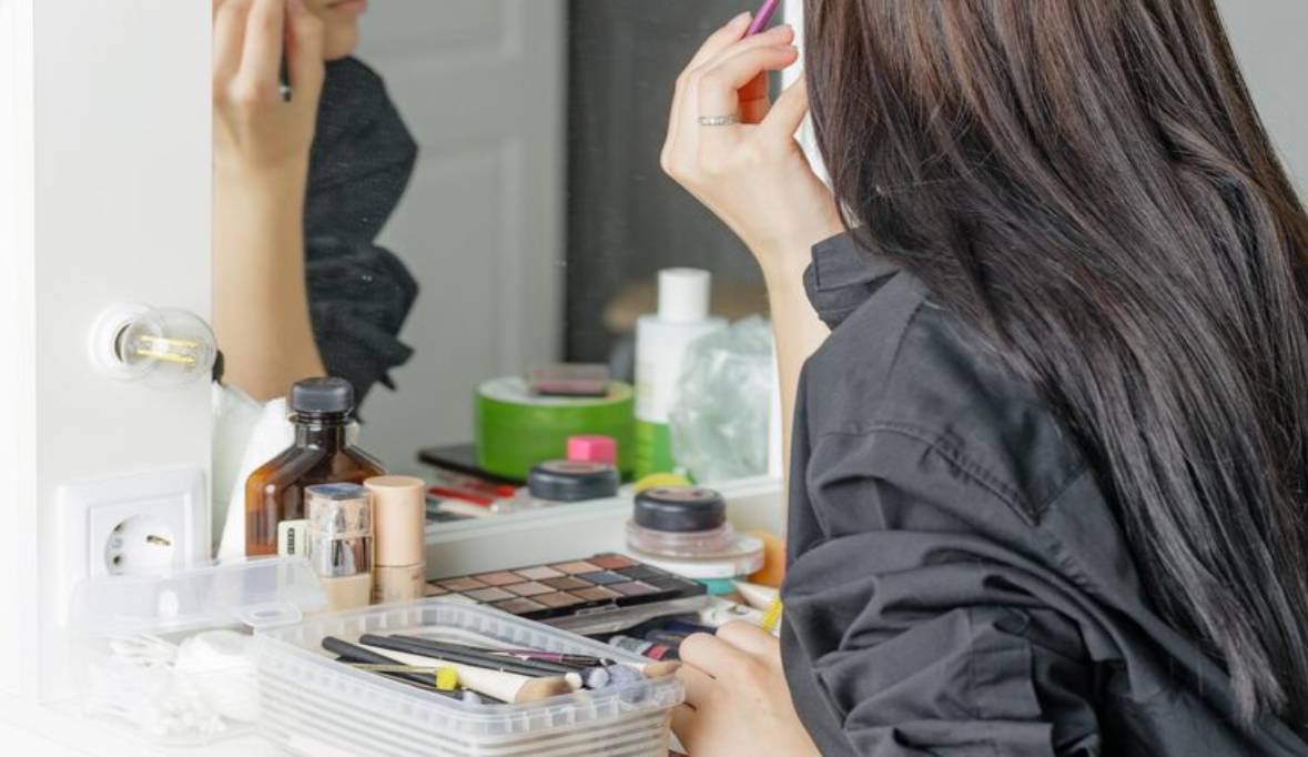 Young girl applies makeup herself home front mirror