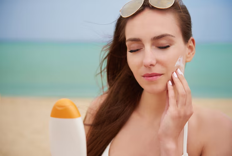 Young beautiful woman applying sun cream beach